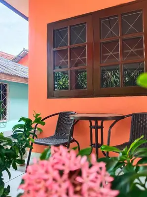 a table and chairs on a porch with pink flowers at Friends Retreat - Phuket Airport in Ban Bo Han