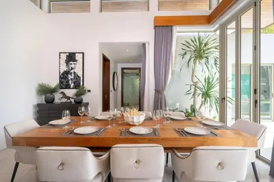 a dining room with a wooden table and chairs at Luxury 4BR Pool Villa Botanica Bangtao Beach in Ban Thalat Choeng Thale
