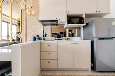 a kitchen with white cabinets and a refrigerator at Bellevue by Villacarte in Laguna Phuket