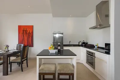 a kitchen with a counter and a table in it at Tropical Serenity - Elegant 1 Bedroom with Pool in Ban Saiyuan (1)