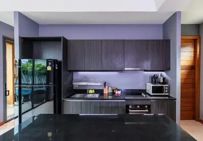 a kitchen with dark wood cabinets and a microwave at Villa Coco - Classy Modern 2 Bedroom Pool Villa in Ban Saiyuan (1)