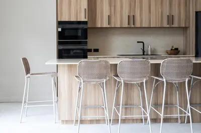 a kitchen with four bar stools in front of a counter at Villa Chang Thai - Stylish 3 Bedrooms with Private Pool in Rawai Beach