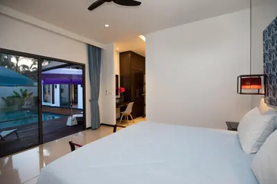 a bedroom with a bed and a view of a pool at Villa Dinadi - Superb 2 Bedrooms Pool Villa in Rawai Beach
