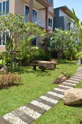 a garden with a stone path in front of a building at David Residence in Nai Yang Beach