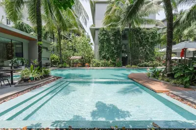 a swimming pool with palm trees and a building at Diamond Resort Phuket walk to Bangtao Beach in Phuket