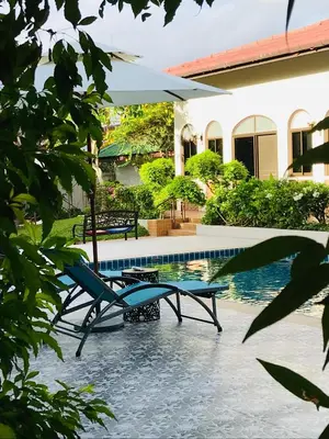 a pool with two chairs and a table next to it at Green View suite with private bathroom and kitchen in Ban Phlu Yai