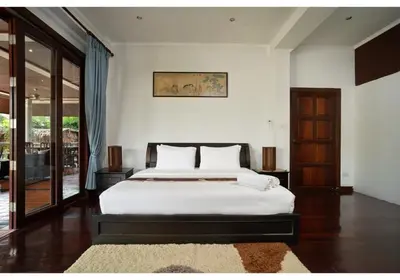 a bedroom with a bed with white sheets and a rug at Lumaya Rawai in Rawai Beach