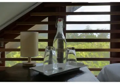 a bottle and two glasses on a table with a lamp at Lumaya Rawai in Rawai Beach