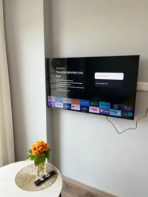 a vase of flowers on a table with a tv at UPMOON Hotel Chalong Phuket in Ban Suan