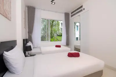 two beds in a white room with a window at 3-BR Condo Mountain & Pool view, Pool & Gym access - Kamala Hills G201 in Kamala Beach