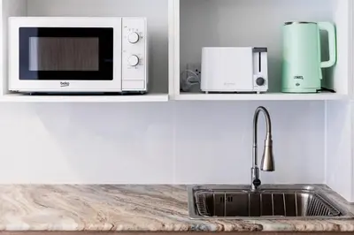 a kitchen counter with a sink and a microwave at The Signature Suite in Ban Mai Salae