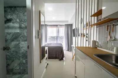 a kitchen with a sink and a bed in a room at North Gate Apartments in Ban Mai Salae