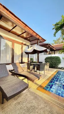 a patio with chairs and an umbrella and a pool at Phuket Cozy Villa Pasak4 Green Garden BangTao in Laguna Phuket