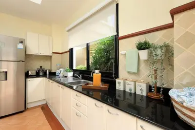 a kitchen with white cabinets and black counter tops at Laguna Golf View Pool Villa in Ban Thalat Choeng Thale