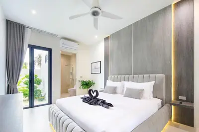 a bedroom with a large white bed with a ceiling fan at Luxury Modern Villa Phuket - Thala in Phuket