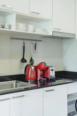 a kitchen with white cabinets and red appliances on the counter at D401 Title Rawai Beach Front 2 Bedroom Apartment in Rawai Beach