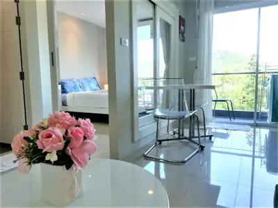 a vase with pink flowers on a table in a room at A Fully Furnished Condo in the Phuket Center in Ban Ket Ho