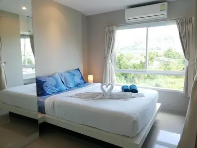a bedroom with a bed with blue pillows and a window at A Fully Furnished Condo in the Phuket Center in Ban Ket Ho