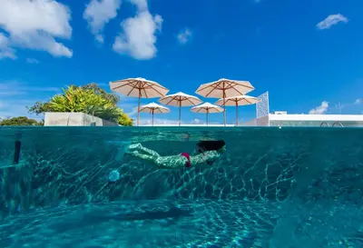 a person swimming in a swimming pool with umbrellas at Duplex Loft near Nai Harn Beach with Pools & Gym - Utopia Loft B125 in Rawai Beach