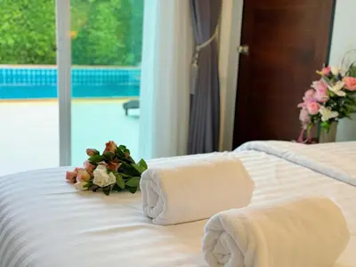 two beds with towels and flowers on top of them at shine bright villa in Ban Saiyuan (1)