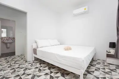 a white bedroom with a white bed with two towels on it at Seaside house in Ban Thalat Choeng Thale