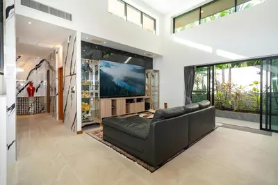 a living room with a couch and a large screen tv at Noi's Villa - tropical oasis with pool and maid in Kamala Beach