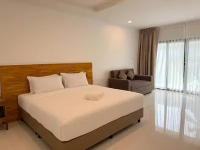 a bedroom with a large bed and a chair at Veeyava Bangtao House in Surin Beach