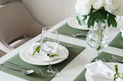 a table with white plates and glasses and flowers at The Ozone Terracotta Art Golf View Bangtao in Laguna Phuket