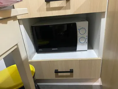 a microwave sitting in a cabinet in a kitchen at The title rawai in Ban Saiyuan (1)