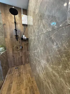 a bathroom with a shower with a stone wall at Rinda House Patong 31 in Patong Beach