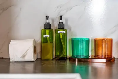two green bottles sitting next to a roll of toilet paper at The Outdoor Kata Hotel in Kata Beach