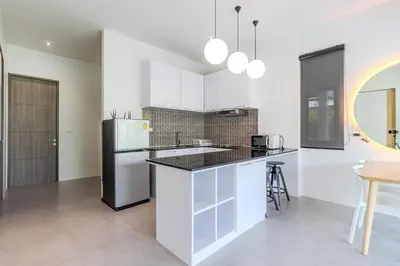 a kitchen with white cabinets and a black and white refrigerator at V242 Prime Location 2BR with Pool&Garden Near Beach in Bang Tao Beach