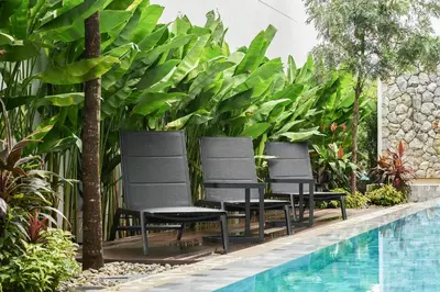 three chairs sitting next to a swimming pool at Trinity 4 BDR POOL Villa in Ban Pak Lak