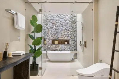 a bathroom with a tub and a stone wall at Trinity 4 BDR POOL Villa in Ban Pak Lak
