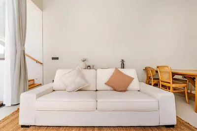 a white couch in a living room with a table at Qabalah by Villacarte in Ban Pak Lak