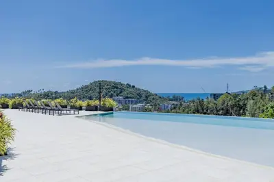 a swimming pool with chairs and a mountain in the background at Beautiful Andamaya sea view in Ban Thalat Choeng Thale