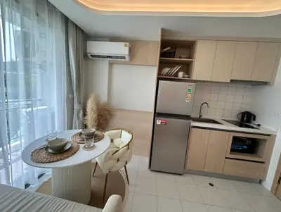 a small kitchen with a table and a refrigerator at Fantasea Condo Kamala in Kamala Beach