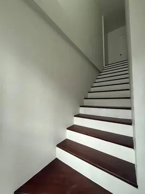 a staircase in a house with white walls and wooden floors at Town House European Style in Ban Ket Ho