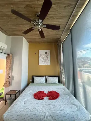a bedroom with a bed with a ceiling fan at The Buddha Rawai Villa in Ban Saiyuan (1)