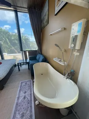 a bathroom with a tub in a room with a couch at The Buddha Rawai Villa in Ban Saiyuan (1)