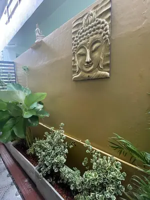 a gold mask on the side of a wall with plants at The Buddha Rawai Villa in Ban Saiyuan (1)