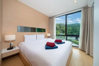 a bedroom with a large bed with red and blue towels on it at Hillside 2BR Apartment with Pool & Gym 5 Min to Kamala Beach 48RK in Kamala Beach
