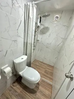 a white bathroom with a toilet and a shower at Bike Works Inn Bang Tao in Ban Thalat Choeng Thale