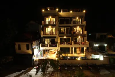 a tall white building with lights on it at night at Duangjai Residence, Rooms & Apartments in Rawai Beach