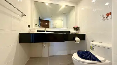 a bathroom with a sink and a toilet and a mirror at Palace - Spacious 1 bedroom Condo with shared Pool in Patong Beach
