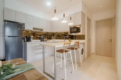 a kitchen with white cabinets and a counter with stools at Cassia Exclusive Lake View Condo Bang Tao Beach in Phuket Town