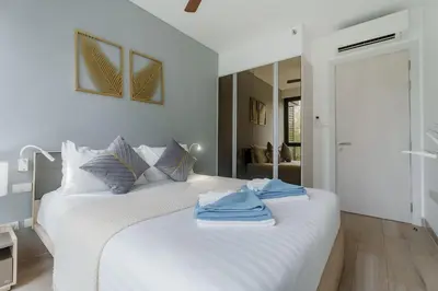a bedroom with a white bed with towels on it at Cassia Exclusive Lake View Condo Bang Tao Beach in Phuket Town