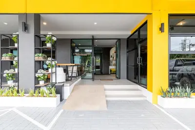 an entrance to a building with yellow walls and plants at Phuket Five Fortune Holiday Hotel in Rawai Beach