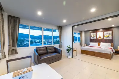 a bedroom with a bed and a couch and a desk at Phuket Five Fortune Holiday Hotel in Rawai Beach