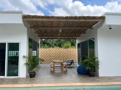 a patio with a wooden table and chairs at Baan ton mai 2 bedrooms 400 m from the beach in Klong Muang Beach